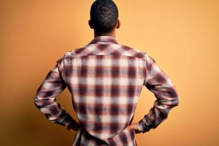 man with hands on hip looking at wall.